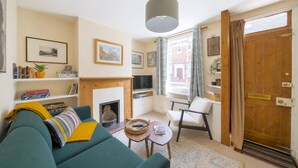 Un salon avec un canapé, un téléviseur, une cheminée et une porte en bois.