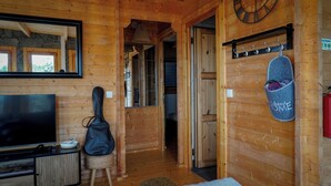 Un interior de madera con televisión, guitarra y felpudo.
