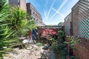 A courtyard with a bicycle, potted plants, and a brick wall. - Beautiful Home in South Bank - Pass the Keys (London)