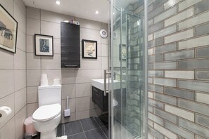 Ein modernes Badezimmer mit Toilette, Waschbecken und Duschbereich.