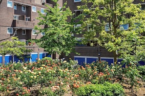A residential building with multiple balconies, a garden with various flowering plants, and a brick facade. - Beautiful Home in South Bank - Pass the Keys (London)