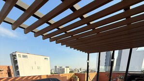 A rooftop patio with a pergola, outdoor furniture, and potted plants. - LUUM 402 (Guadalajara)