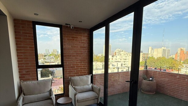 A balcony with two chairs, a small table, and a potted plant. - LUUM 402 (Guadalajara)