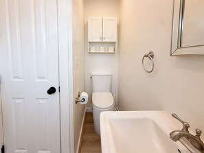 A bathroom with a toilet, a sink, and a mirror. - Seal Beach Comfort Retreat (Seal Beach)