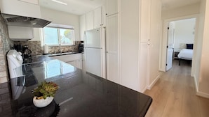 Una cocina moderna con armarios blancos, encimera negra y estufa integrada.