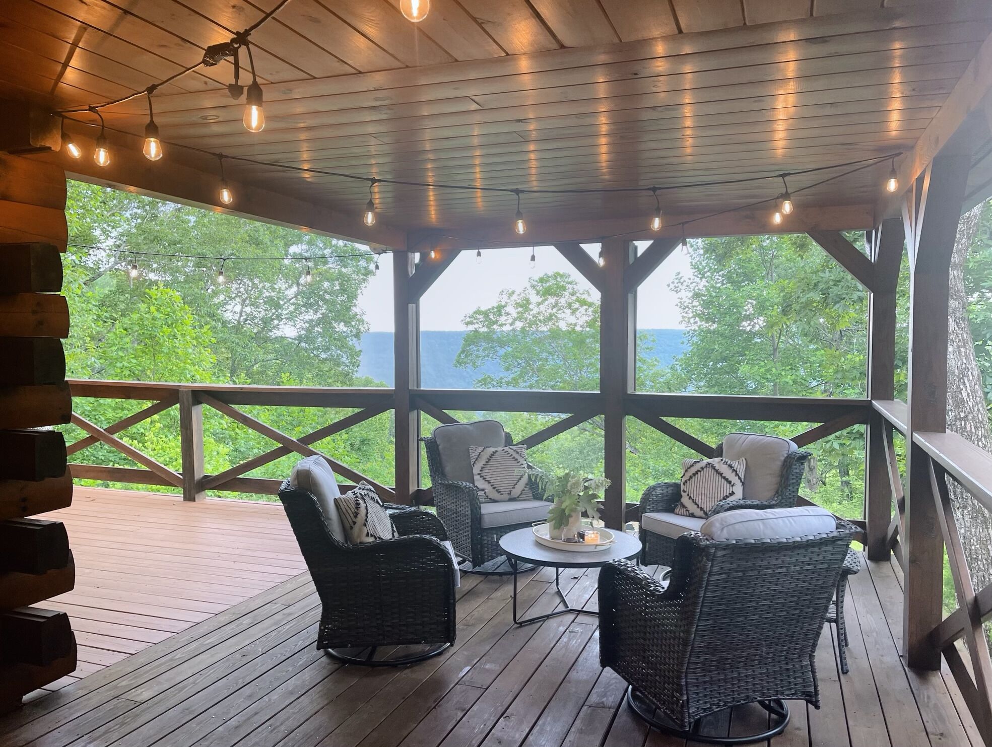 A covered outdoor seating area with wicker furniture and string lights.