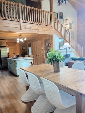 A spacious kitchen with wooden cabinets, a dining area with wicker chairs, a wooden staircase, and a view of the living area. - Mossy Falls - Bluff Views, Hot Tub & Waterfall (Altamont)