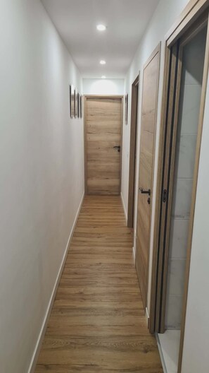 Ein Flur mit Holzboden, weißen Wänden und Türen an beiden Seiten.