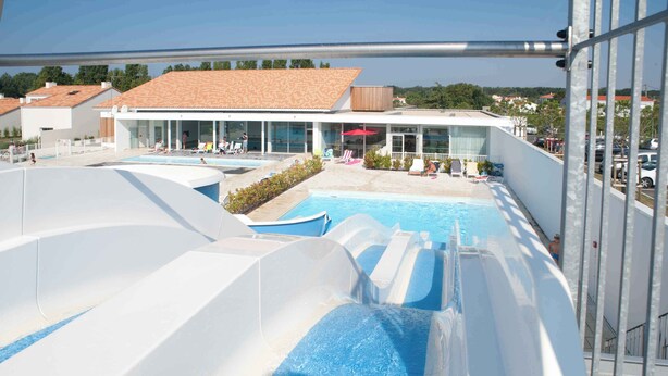 A water park with multiple slides and pools, a covered area with seating, and a building with large windows.