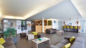 A spacious lobby with seating areas, a reception desk, and a bar area.