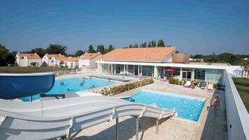 Ein Resort mit Schwimmbad, Liegestühlen und einer Rutsche.