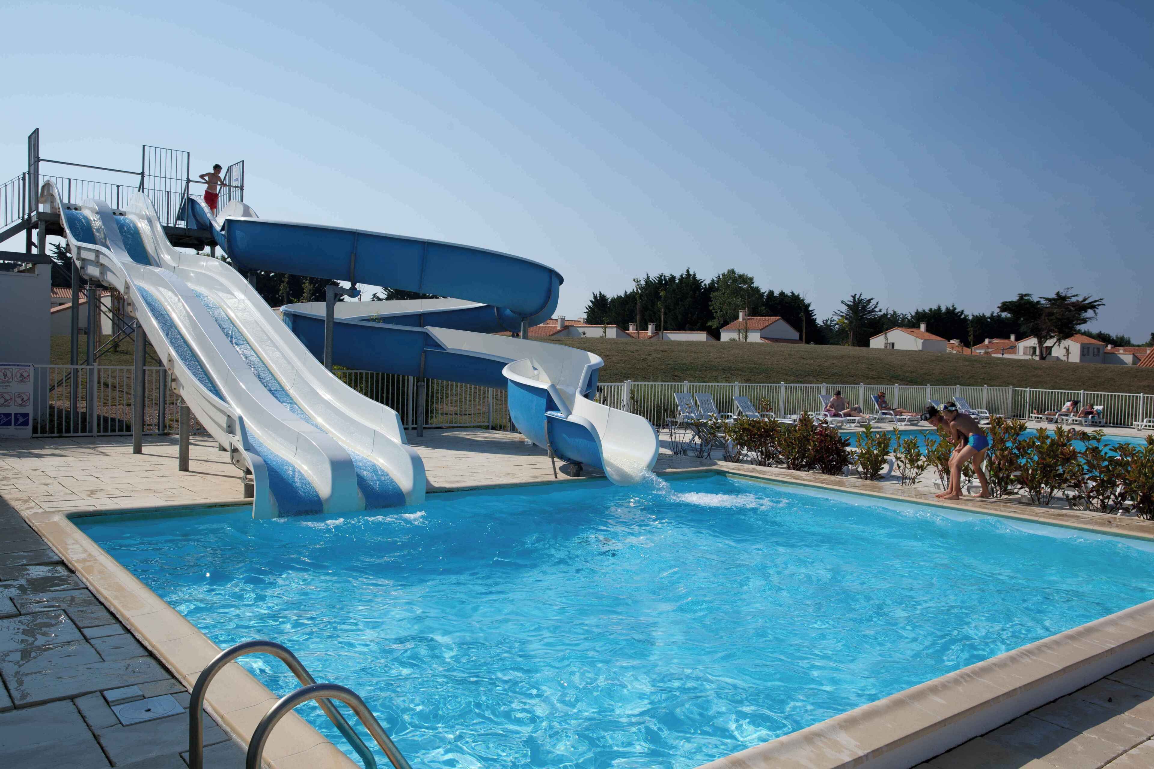 Une piscine dotée de plusieurs toboggans et d’un espace aménagé au bord de la piscine.