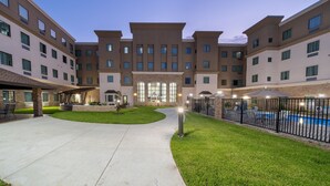 A hotel with a courtyard, a swimming pool, and a covered seating area. - Mobility Accessible Studio Suite w/ Free Breakfast (Baytown)