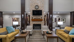 A lobby with a stone fireplace, two sofas, a television, and a sign for the pantry.