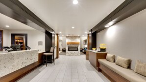 A hotel lobby with a reception desk, seating area, and a fireplace.