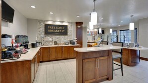 A modern kitchen with a 'FREE DAILY BREAKFAST' sign, wooden cabinets, and a central island.