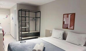 Habitación de hotel con una cama, un armario, un cuadro y una puerta con un cartel de no fumar.