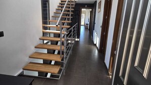 A modern interior with a wooden staircase, dark tiled flooring, and a sleek door. - BEAUTIFUL VILLA  FOR 10 PERSONS, 3 KM FROM THE BEACH OF LLORET IN QUIET LOCATION (Lloret de Mar)