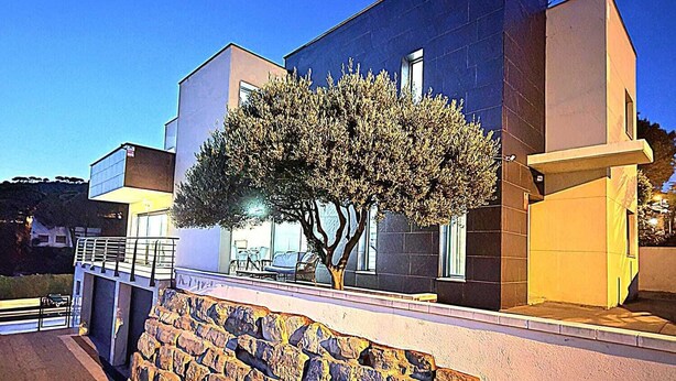 A modern building with a stone retaining wall and a tree in front. - BEAUTIFUL VILLA  FOR 10 PERSONS, 3 KM FROM THE BEACH OF LLORET IN QUIET LOCATION (Lloret de Mar)