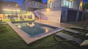 A modern two-story house with a swimming pool, outdoor seating, and a well-lit staircase. - BEAUTIFUL VILLA  FOR 10 PERSONS, 3 KM FROM THE BEACH OF LLORET IN QUIET LOCATION (Lloret de Mar)