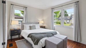 Una camera da letto con un letto, comodini, una panca e vista sull'esterno.