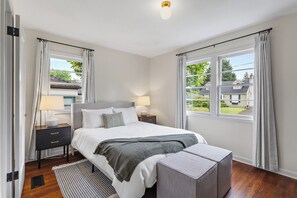 Une chambre à coucher avec un lit, des tables de chevet, un banc et une vue sur l’extérieur.