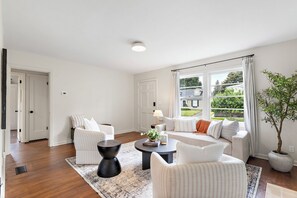Een ruime woonkamer met een zithoek, een salontafel en een potplant.