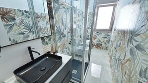 Ein Badezimmer mit einem schwarzen Waschbecken, einem Spiegel und einer Dusche mit Glastüren.