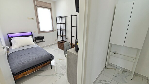 Ein Schlafzimmer mit Bett, Kleiderschrank, Schreibtisch und Fenster.