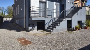 Ein modernes Gebäude mit Treppe, einem kleinen Balkon und Kiesgrund.