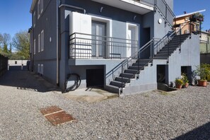 A modern building with a staircase, a small balcony, and a gravel ground. - Newly built room with wifi and large bathroom (Rho)