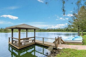 Eine Holzsteg mit einem Pavillon, einem Boot und einem ruhigen See.