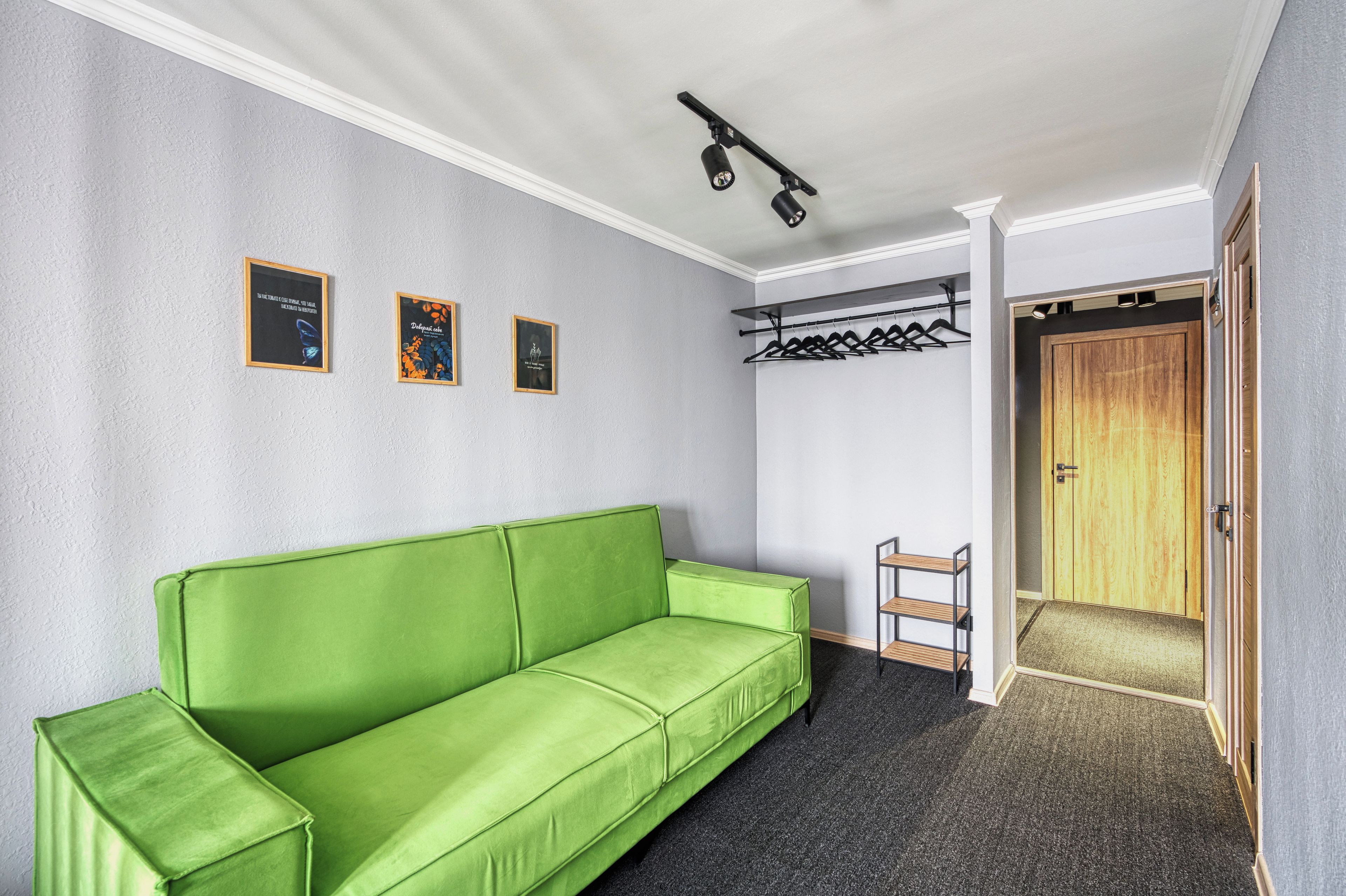 A room with a green sofa, a coat rack, and a wooden door.
