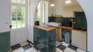 A kitchen with a double door, a sink, a stove, and a trash bin. - GITE IN THE HEART OF THE CEVENNES IDEAL FOR NATURE LOVERS (Génolhac)