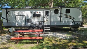 Un camper con angolo cottura, una porta scorrevole e un piccolo tavolo.