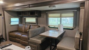 Interni compatti di un camper con angolo cottura, zona salotto e finestre.