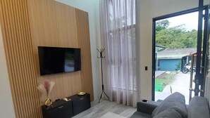 A modern living room with a flat-screen TV, a sofa, a coffee table, and a window with curtains. - Romantic 1-bedroom apartment with AC in fantastic El Castillo (El Castillo)