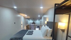 A modern bedroom with a bed, bedside table, and a small seating area with a lamp. - Romantic 1-bedroom apartment with AC in fantastic El Castillo (El Castillo)