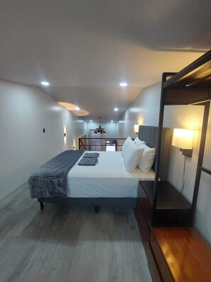 A modern bedroom with a bed, bedside table, and a small seating area with a lamp. - Romantic 1-bedroom apartment with AC in fantastic El Castillo (El Castillo)