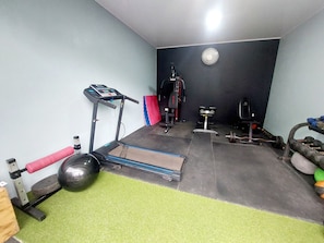 Ein Fitnessraum mit Laufband, Gewichtshocker und unterschiedlichen Trainingsgeräten.