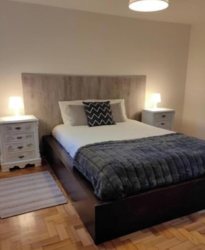 Una camera da letto con un letto, due comodini, un abat-jour e una lampada da terra.