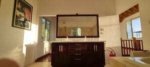 Un baño con un espejo grande, muebles oscuros, un lavamanos y una ducha.