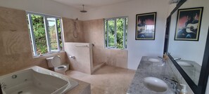 Un baño con bañera, inodoro, ducha y dos lavamanos.