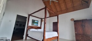 A room with a four-poster bed, a wooden wardrobe, and a ceiling fan.
