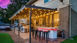 Eine Terrasse im Freien mit Bar, Sitzgelegenheiten und Lichterketten.