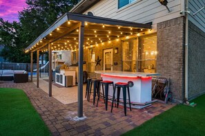 Eine Terrasse im Freien mit Bar, Sitzgelegenheiten und Lichterketten.