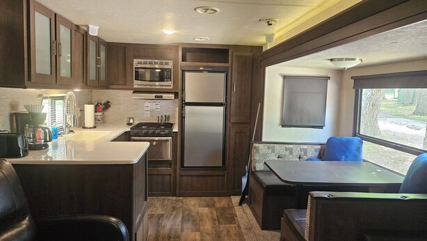 A compact RV kitchen with a stove, microwave, and refrigerator. - Wildwood camper #5  at Heaven's Ridge Campground (Fair Play)