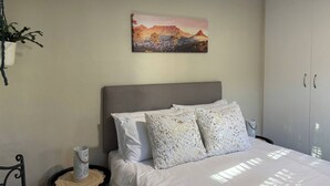 Una camera da letto con un letto, un comodino, una pianta in vaso, un quadro e un armadio.