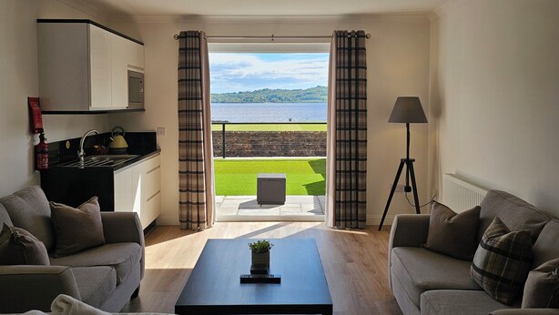 Una sala moderna con vista a un lago, una kitchenette y un comedor.