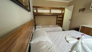 Ein Hotelzimmer mit zwei Betten, einem Holz-Kopfteil und einem kleinen Nachttisch.